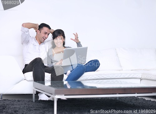 Image of joyful couple relax and work on laptop computer at modern home