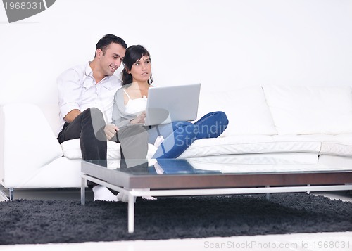 Image of joyful couple relax and work on laptop computer at modern home
