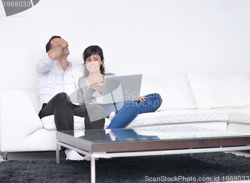 Image of joyful couple relax and work on laptop computer at modern home