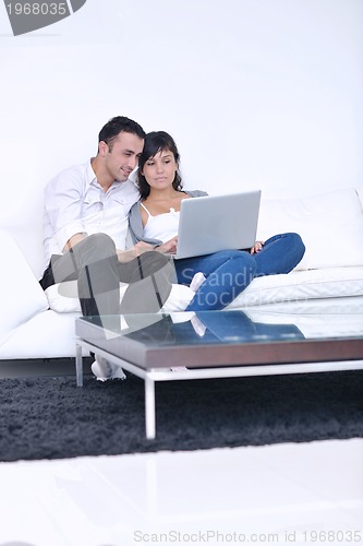 Image of joyful couple relax and work on laptop computer at modern home