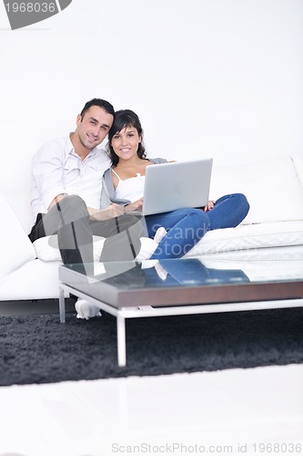 Image of joyful couple relax and work on laptop computer at modern home