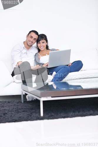 Image of joyful couple relax and work on laptop computer at modern home