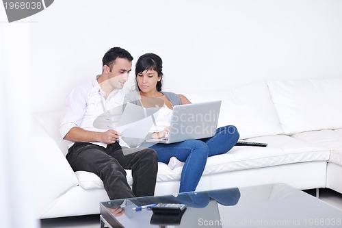 Image of joyful couple relax and work on laptop computer at modern home