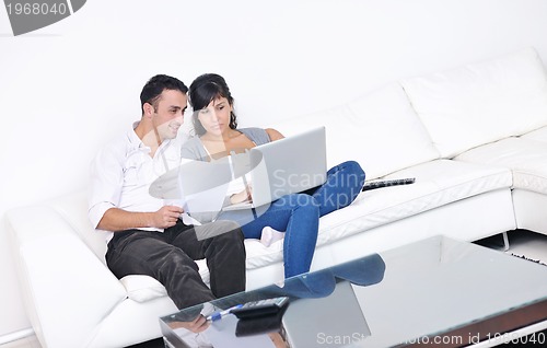Image of joyful couple relax and work on laptop computer at modern home