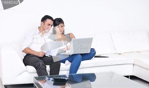 Image of joyful couple relax and work on laptop computer at modern home