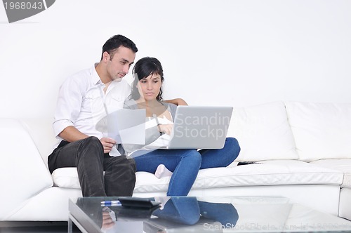 Image of joyful couple relax and work on laptop computer at modern home