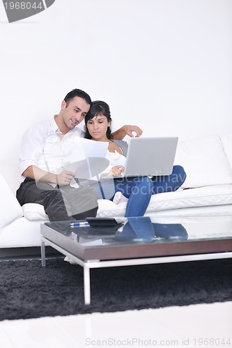 Image of joyful couple relax and work on laptop computer at modern home