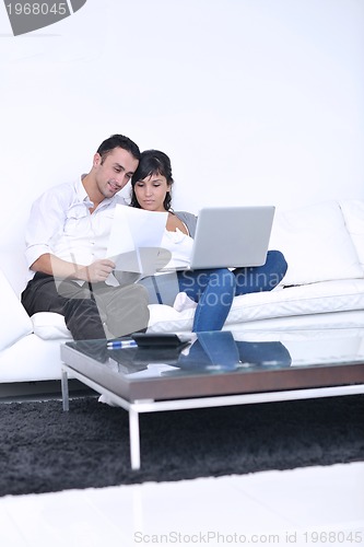 Image of joyful couple relax and work on laptop computer at modern home