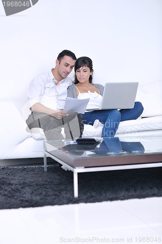 Image of joyful couple relax and work on laptop computer at modern home