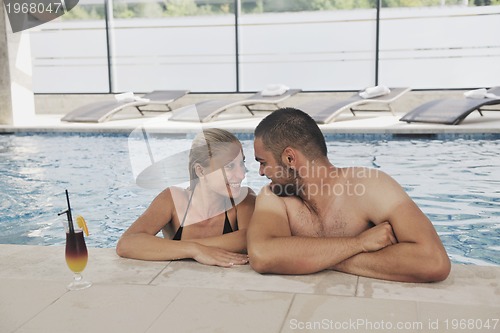 Image of happy cople relaxing  at swimming pool