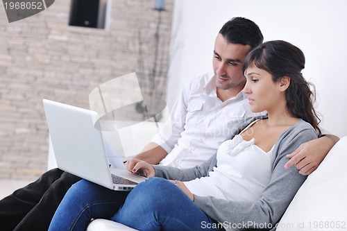 Image of joyful couple relax and work on laptop computer at modern home