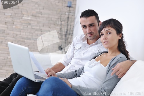 Image of joyful couple relax and work on laptop computer at modern home