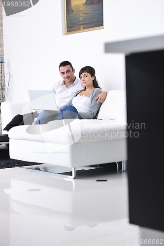 Image of joyful couple relax and work on laptop computer at modern home
