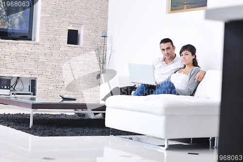 Image of joyful couple relax and work on laptop computer at modern home