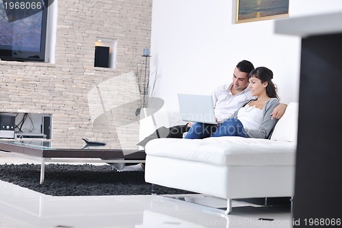 Image of joyful couple relax and work on laptop computer at modern home