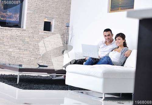 Image of joyful couple relax and work on laptop computer at modern home