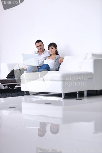 Image of joyful couple relax and work on laptop computer at modern home