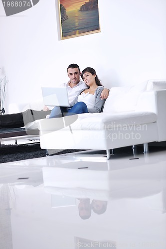 Image of joyful couple relax and work on laptop computer at modern home