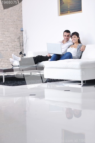 Image of joyful couple relax and work on laptop computer at modern home