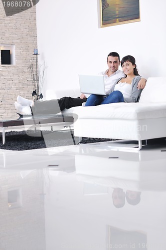 Image of joyful couple relax and work on laptop computer at modern home