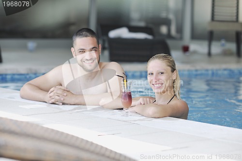 Image of happy cople relaxing  at swimming pool