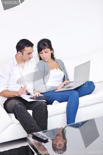 Image of joyful couple relax and work on laptop computer at modern home