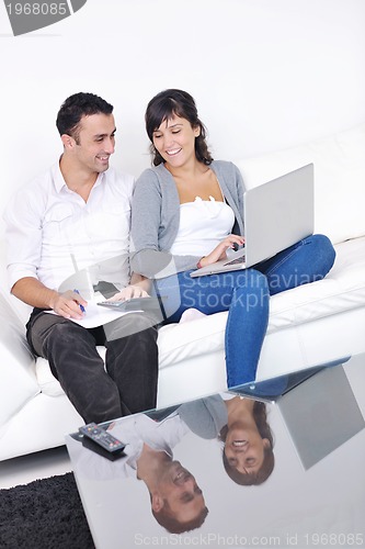 Image of joyful couple relax and work on laptop computer at modern home