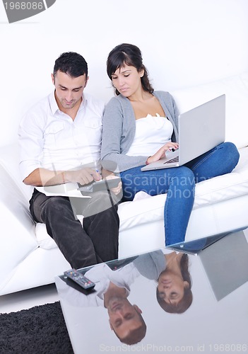 Image of joyful couple relax and work on laptop computer at modern home