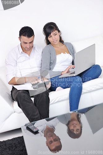 Image of joyful couple relax and work on laptop computer at modern home