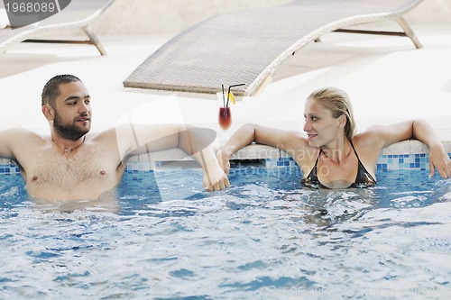 Image of happy cople relaxing  at swimming pool