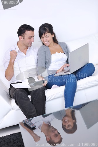 Image of joyful couple relax and work on laptop computer at modern home