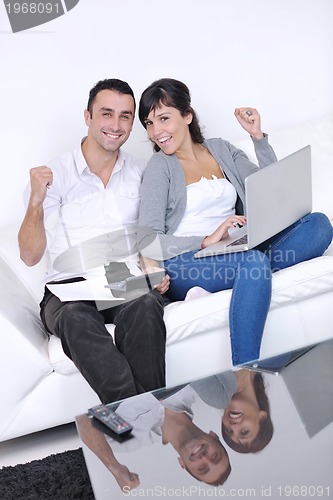 Image of joyful couple relax and work on laptop computer at modern home