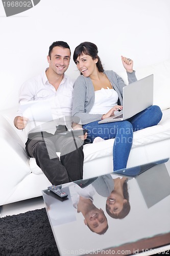 Image of joyful couple relax and work on laptop computer at modern home