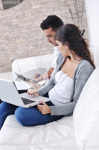 Image of joyful couple relax and work on laptop computer at modern home