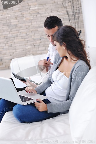 Image of joyful couple relax and work on laptop computer at modern home