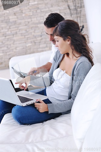 Image of joyful couple relax and work on laptop computer at modern home