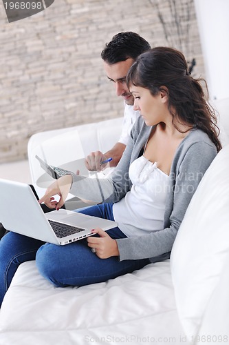 Image of joyful couple relax and work on laptop computer at modern home