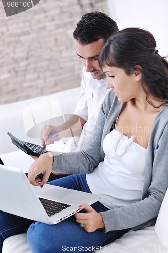 Image of joyful couple relax and work on laptop computer at modern home