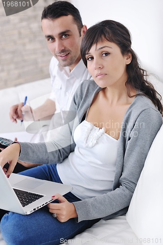 Image of joyful couple relax and work on laptop computer at modern home