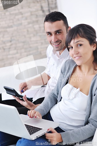 Image of joyful couple relax and work on laptop computer at modern home