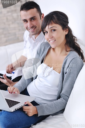 Image of joyful couple relax and work on laptop computer at modern home