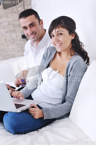 Image of joyful couple relax and work on laptop computer at modern home