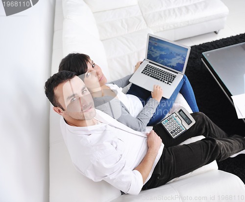 Image of joyful couple relax and work on laptop computer at modern home