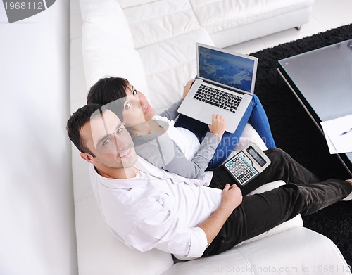 Image of joyful couple relax and work on laptop computer at modern home