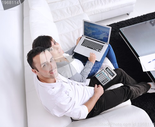 Image of joyful couple relax and work on laptop computer at modern home
