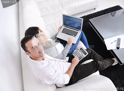 Image of joyful couple relax and work on laptop computer at modern home