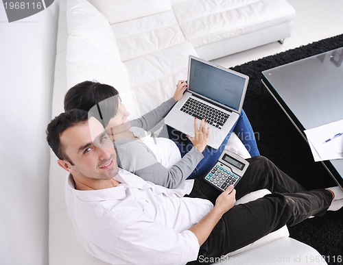 Image of joyful couple relax and work on laptop computer at modern home
