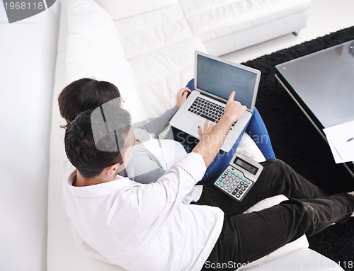 Image of joyful couple relax and work on laptop computer at modern home