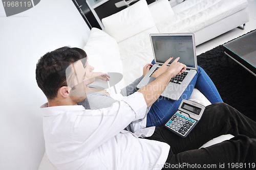 Image of joyful couple relax and work on laptop computer at modern home