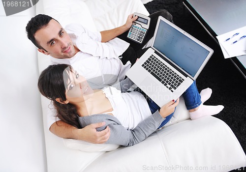 Image of joyful couple relax and work on laptop computer at modern home